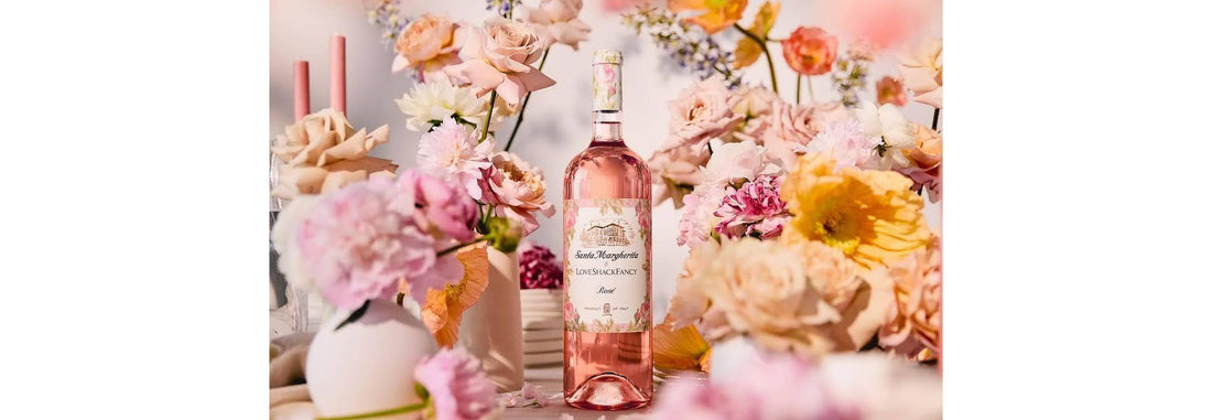 Santa Margherita x LoveShackFancy limited-edition rosé bottle and floral gift box displayed on a romantic tablescape with pastel flowers and candles.